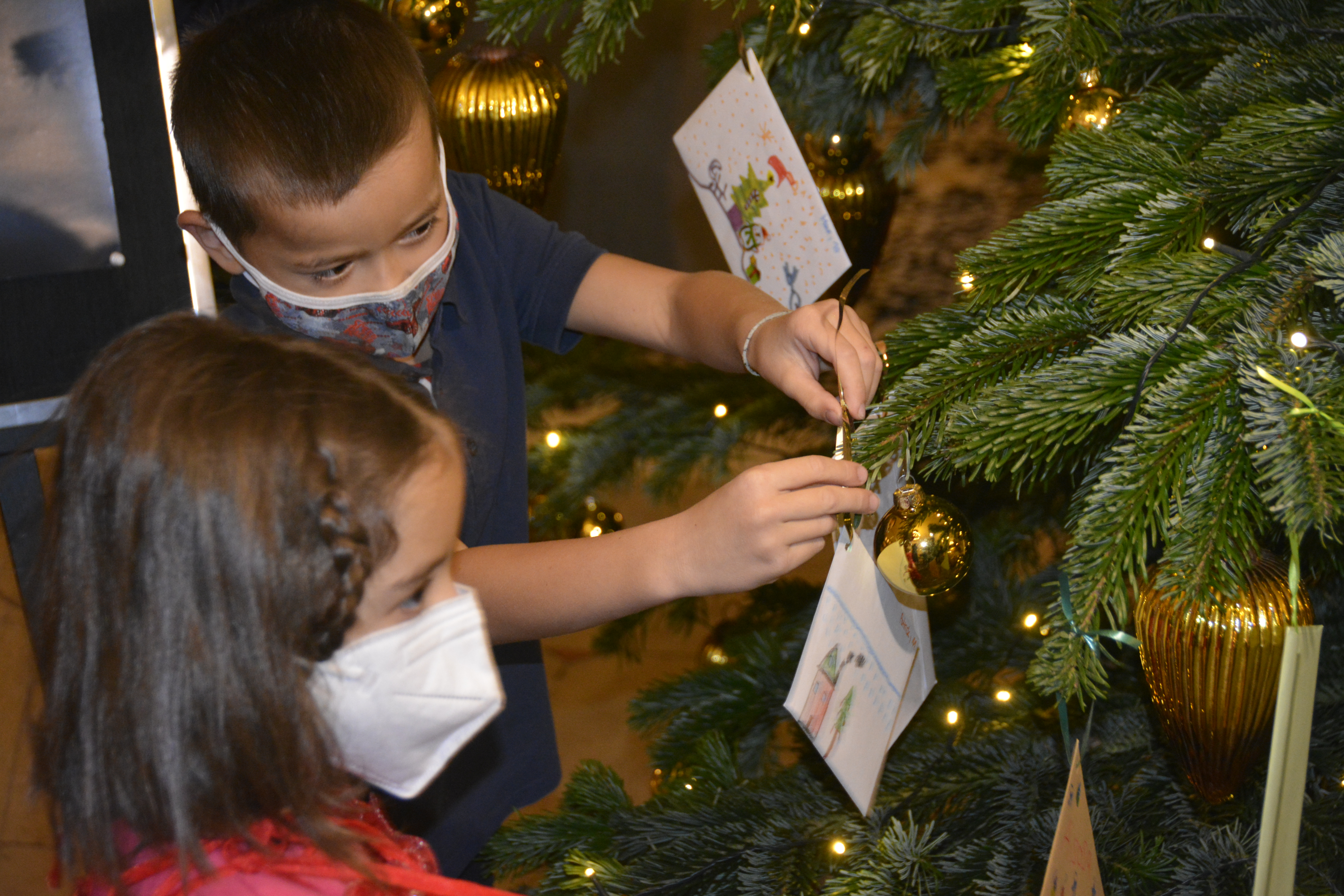 Luca (6) und Maya (6) dürfen gemeisam mit Maha (9) und Hijran (7) stellvetretend für alle 58 Kinder aus dem Frère-Roger-Kinderzentrum die Wünsche aufhängen. Foto: KJF Augsburg/Jasmin Mächtlinger