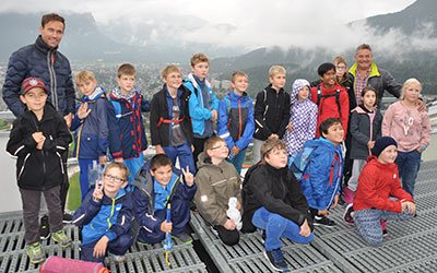 Gruppenbild auf der Sprungschanze: Die Kinder mit dem ehemaligen Skispringer Sven Hannawald (links) und dem Präsidenten der Vierschanzentournee Michael Maurer. 